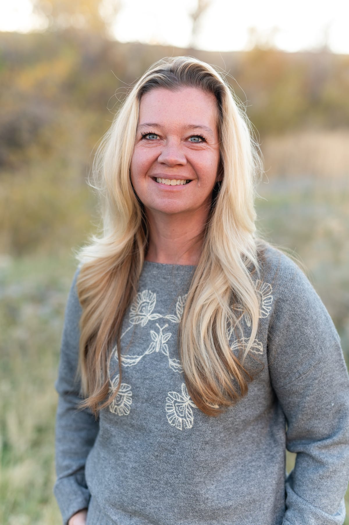 BenNi Gage smiling, with golden autumn trees behind her