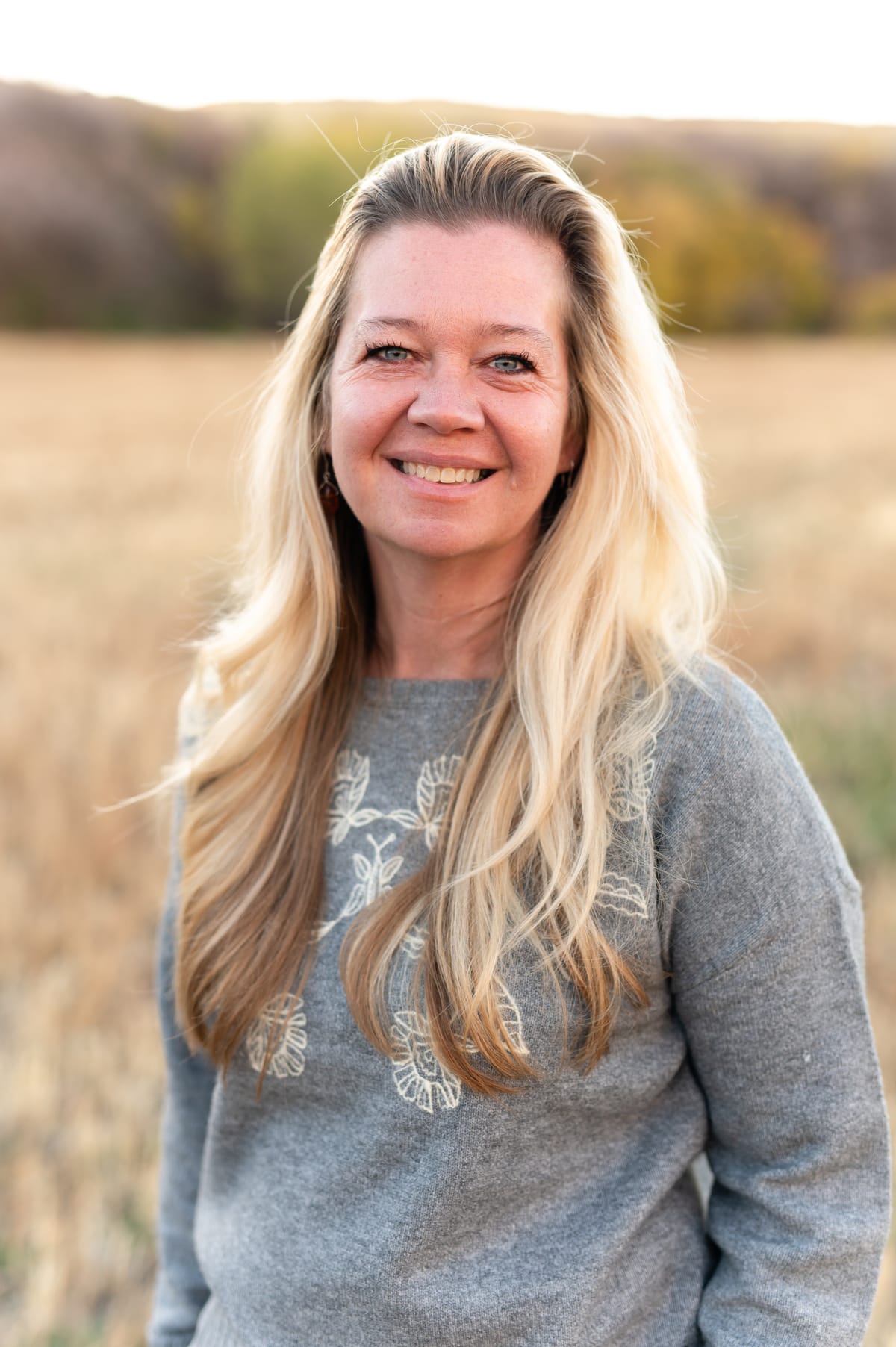 BenNi Gage smiling in a golden field at sunset