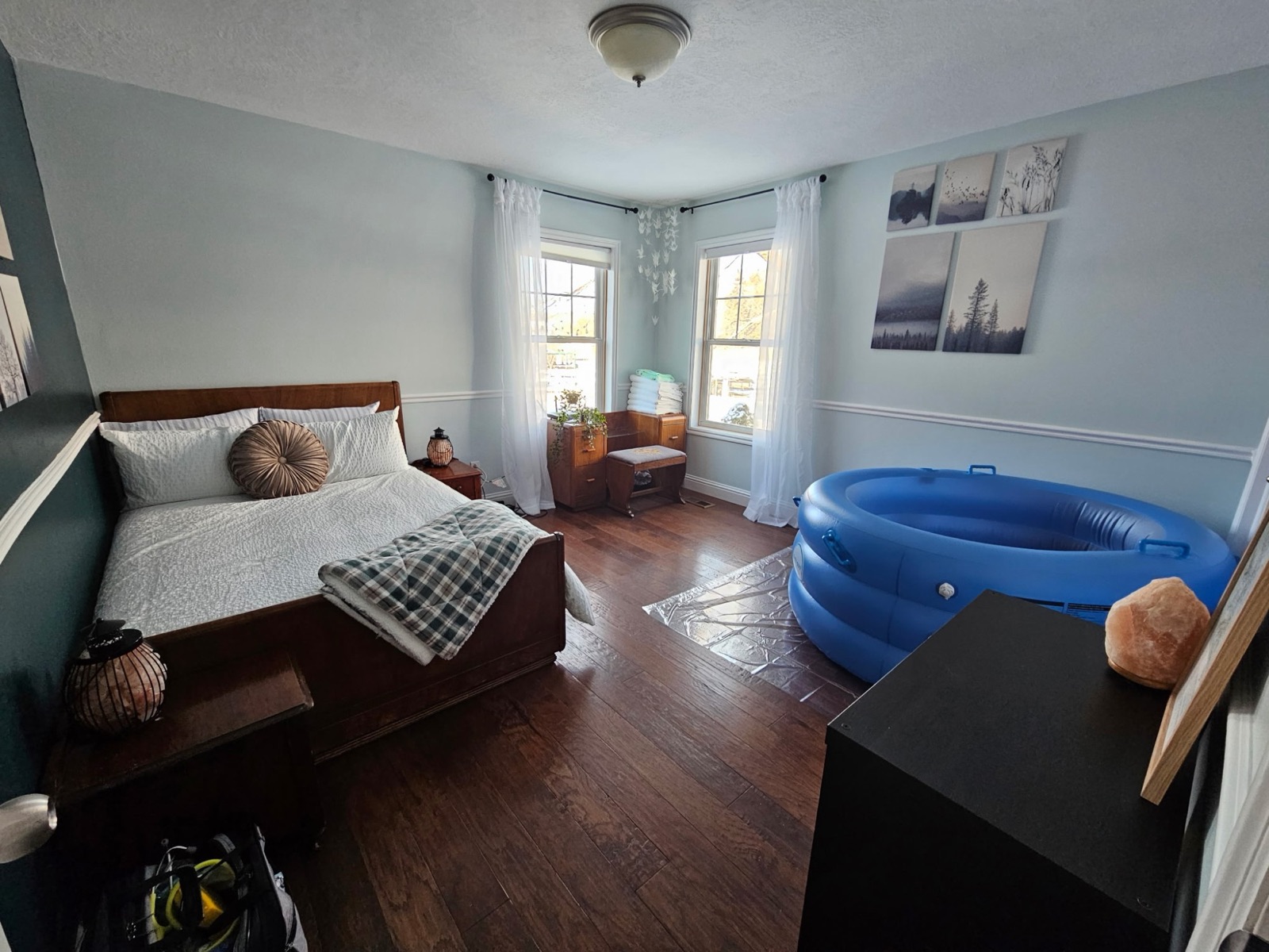 A bedroom prepared for a home birth, with an inflated birth pool, fresh linens, folded towels, and soft salt-lamp light